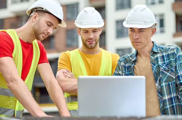 focused engineer two builders hardhats safety vests using computer construction site 259150 52669